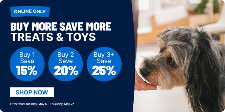 Online-only promotion banner reading &lsquo;Buy More Save More Treats & Toys.&rsquo; Three blue circles state: &lsquo;Buy 1 Save 15%,&rsquo; &lsquo;Buy 2 Save 20%,&rsquo; and &lsquo;Buy 3+ Save 25%.&rsquo; A &lsquo;Shop Now&rsquo; button appears below. On the right, a small black-and-gray dog is being hand-fed a treat indoors. Fine print notes the offer is valid May 5&ndash;7.